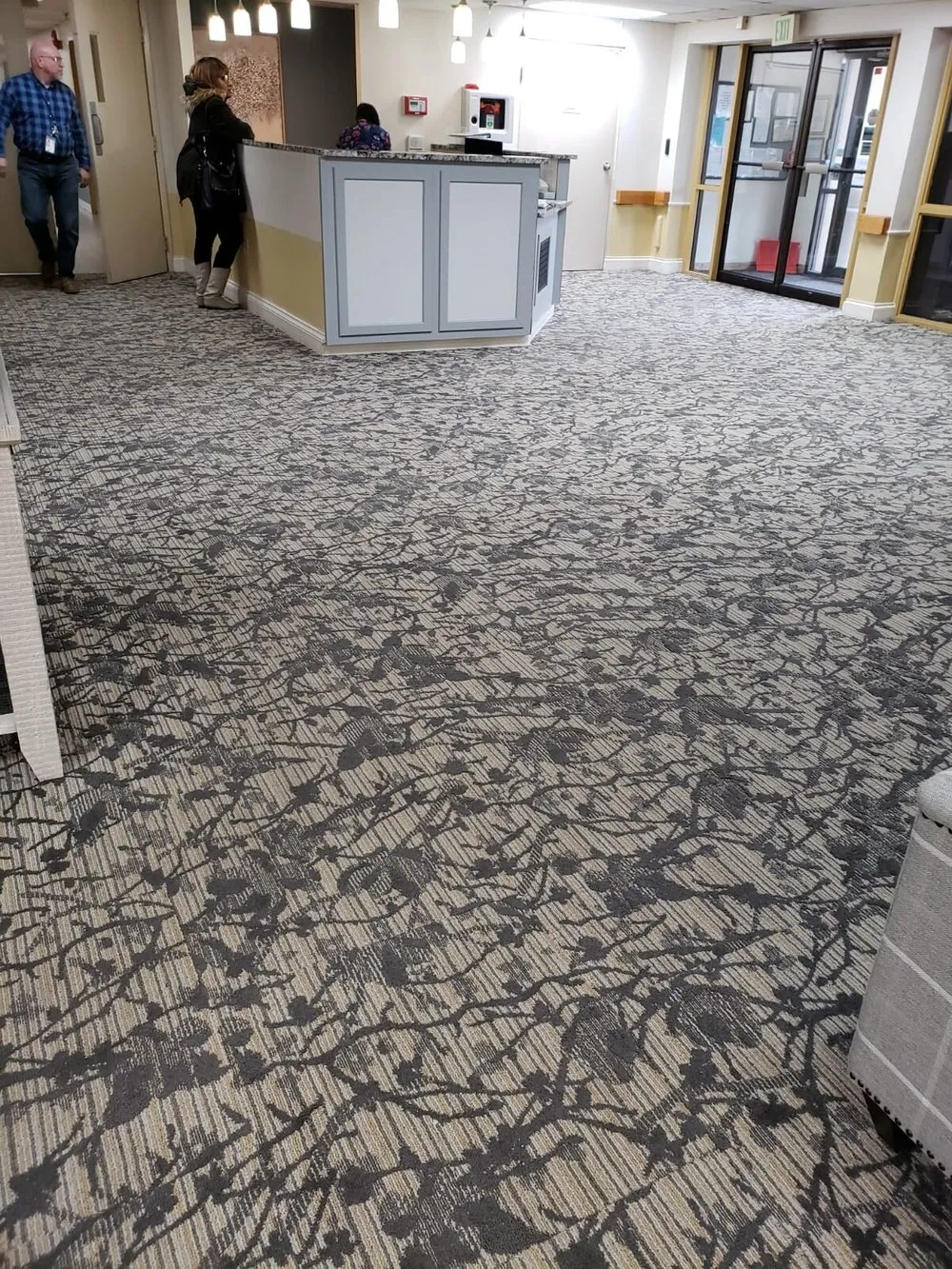 A care-center lobby with a large patterned carpet, a reception desk, and doors to the corridor.
