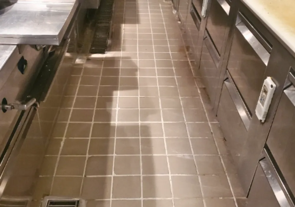 Gray quarry tile floor between stainless steel counters in a commercial kitchen.