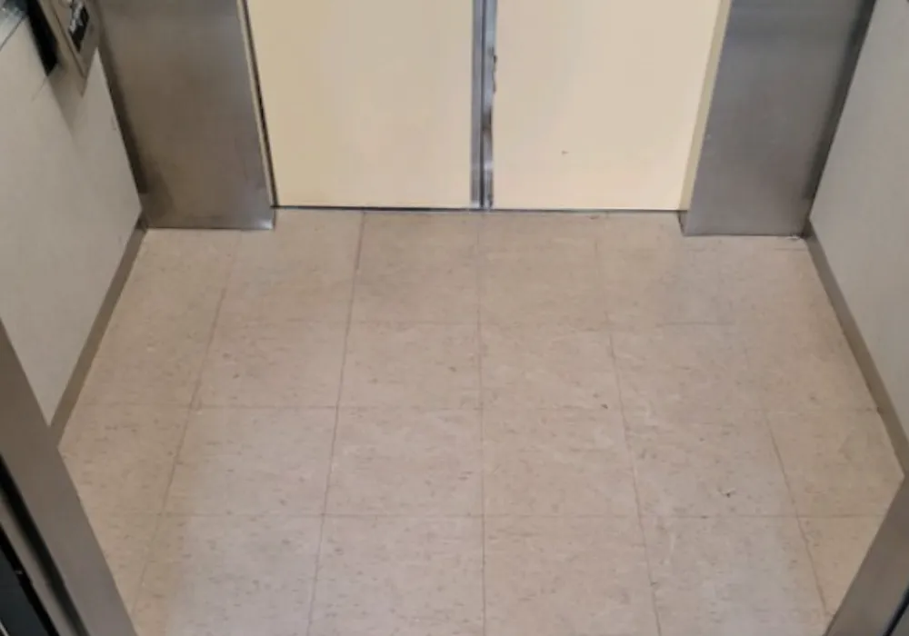 Speckled tile floor inside an elevator with cream doors at West Chester University.